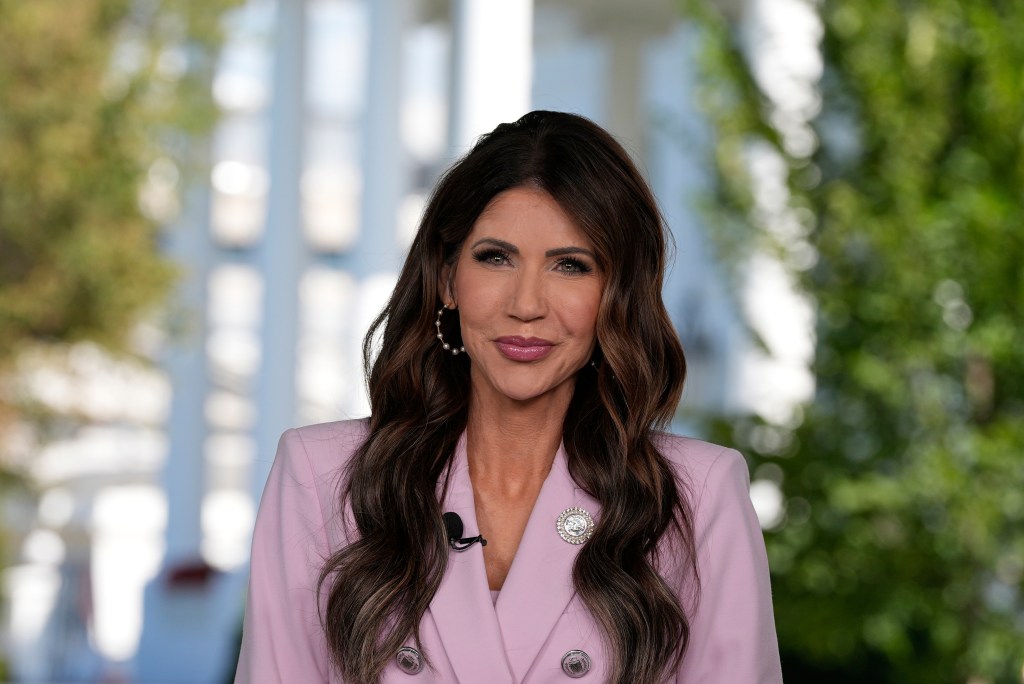 Kristi Noem in a pink blazer, giving an interview at the White House.