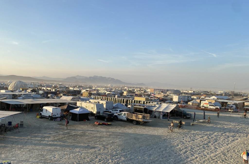 Aerial view of a desert camp with RVs, tents, and people.