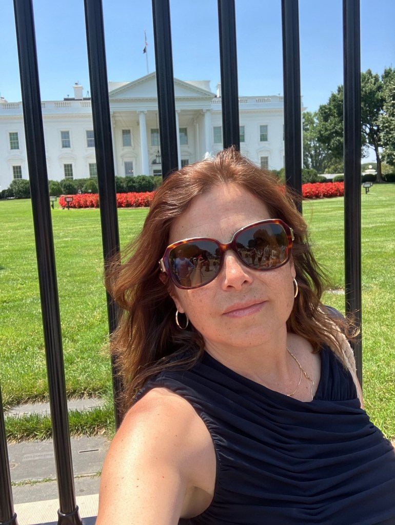 Woman in sunglasses posing in front of the White House.