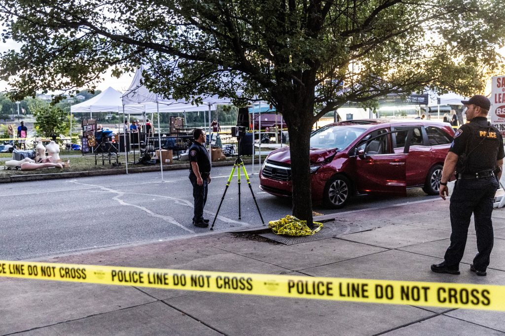 Police officers at the scene of a car crash at a festival.