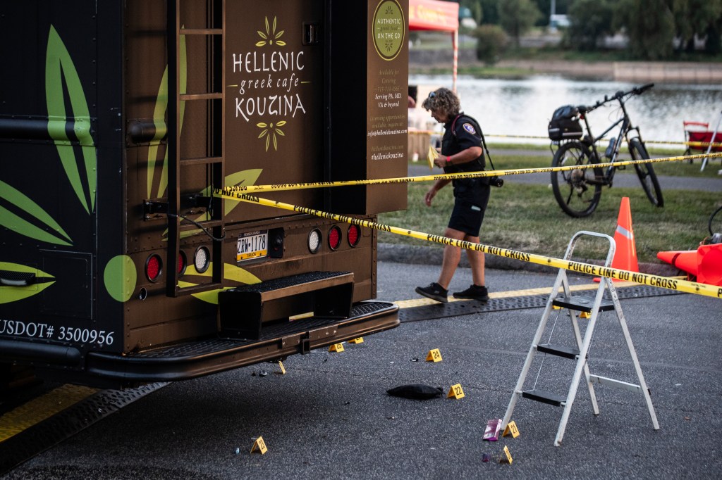 Police investigate a crime scene near a food truck.