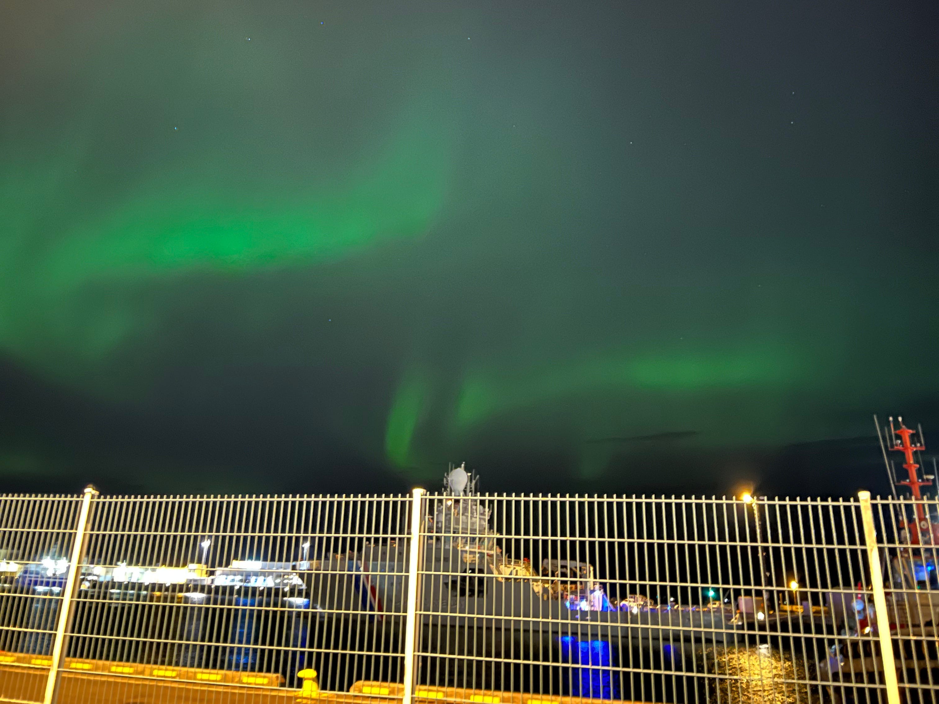 The northern lights above a fence.