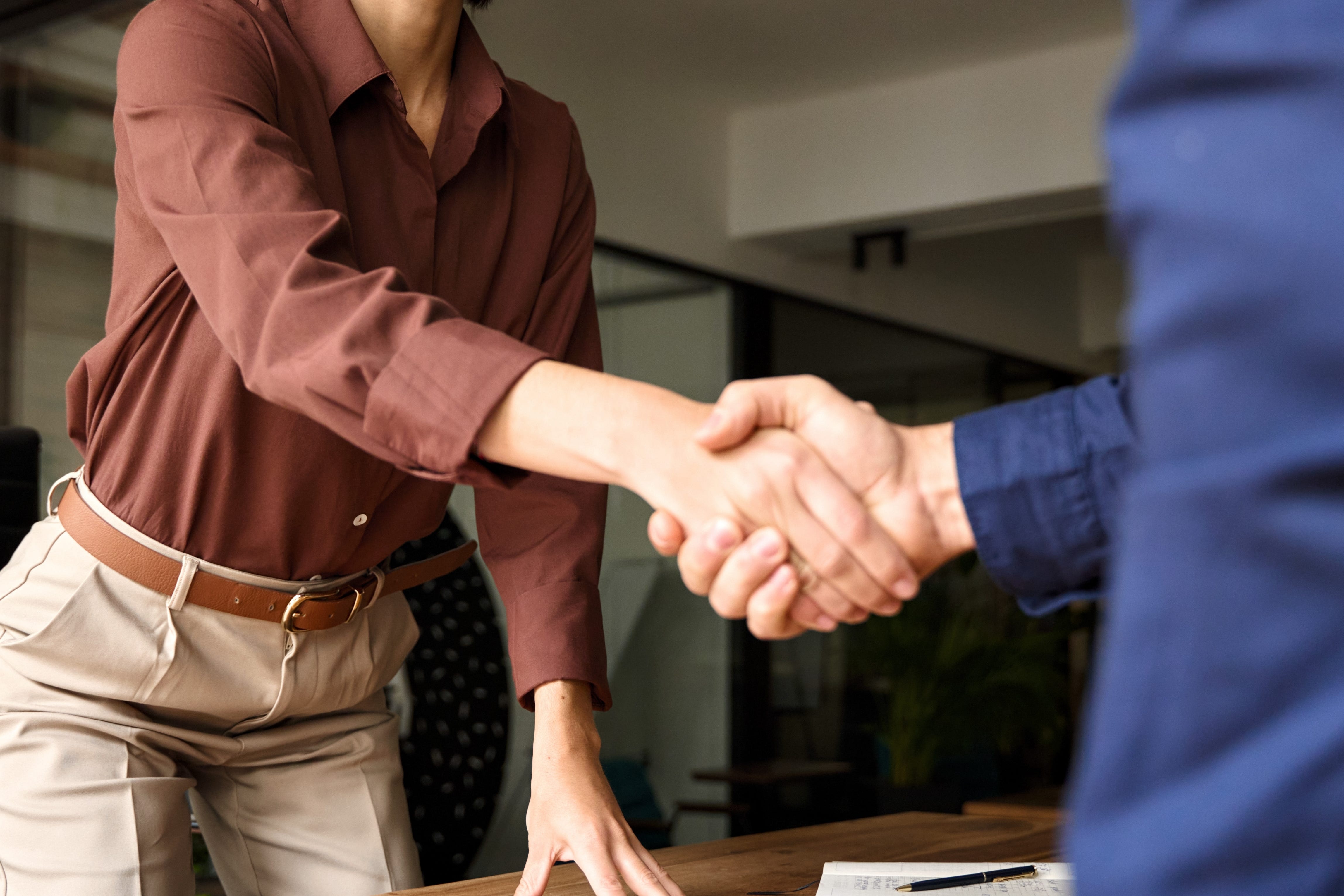 A woman shaking someone's hand from across a desk.