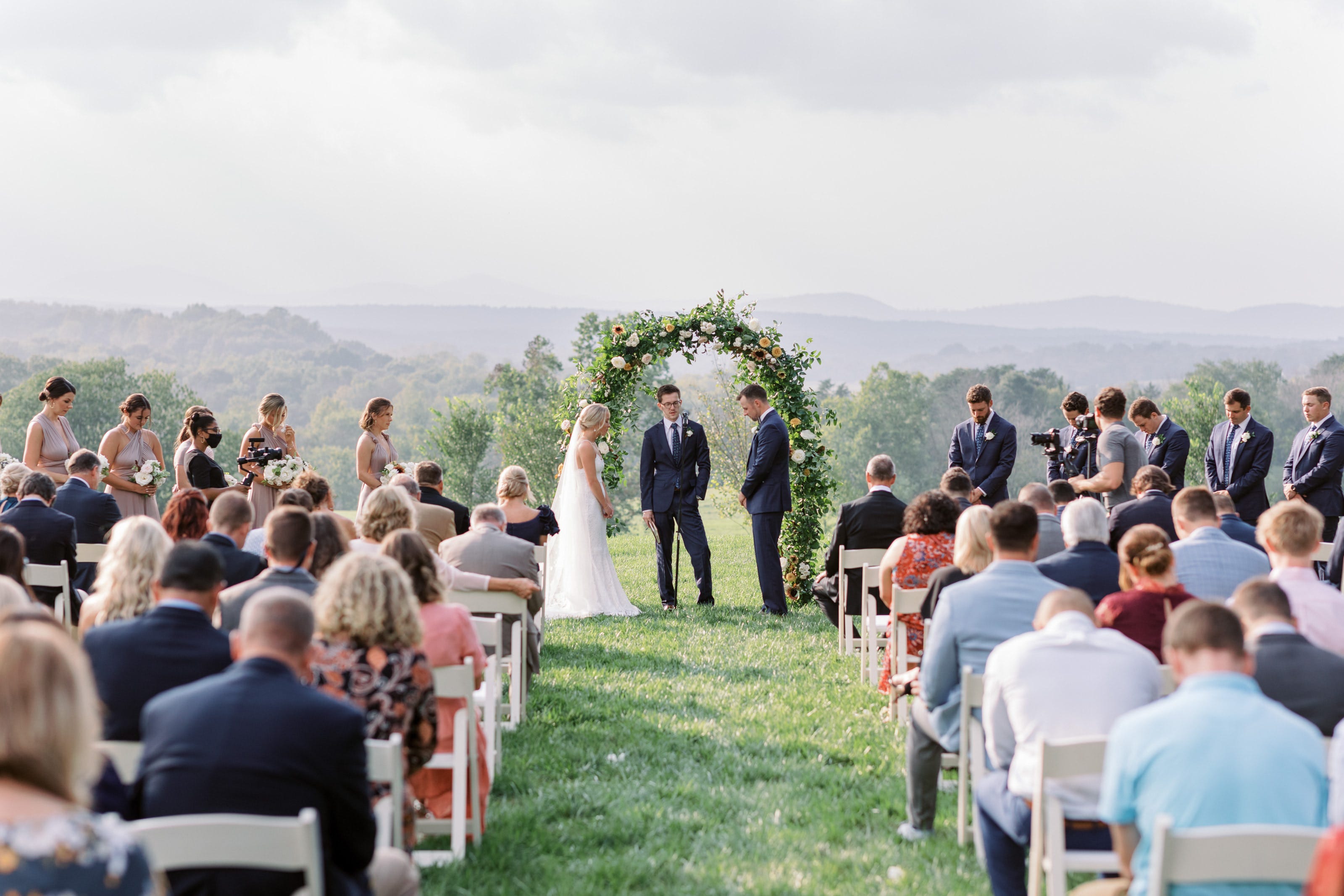 Abby Price and husband standing in front of greenery arch on wedding day