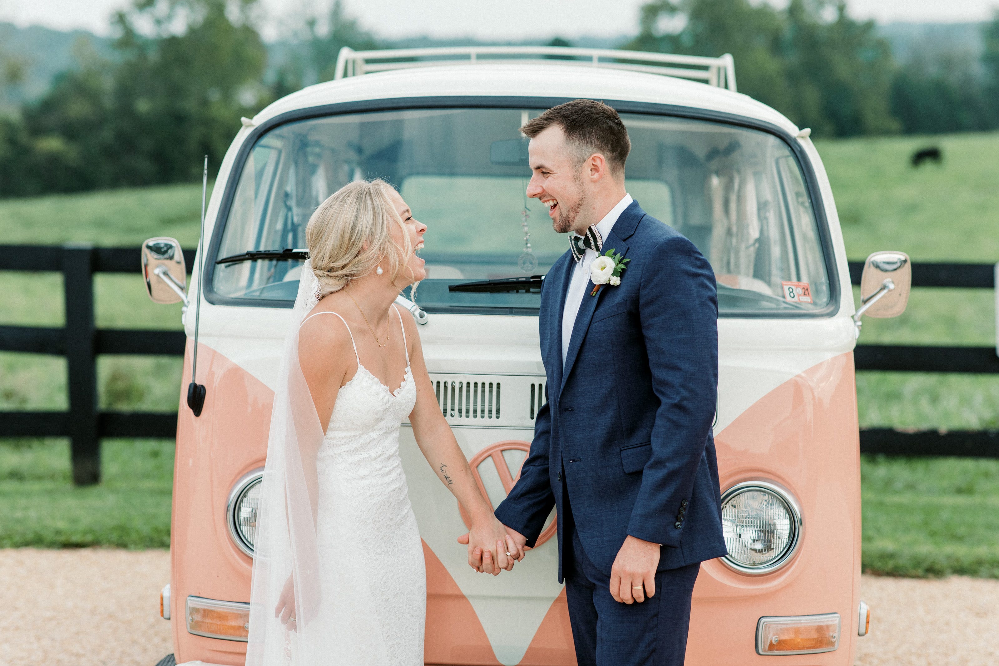 Author Abby Price and husband laughing in front of vintage peach-colored Volkswagen
