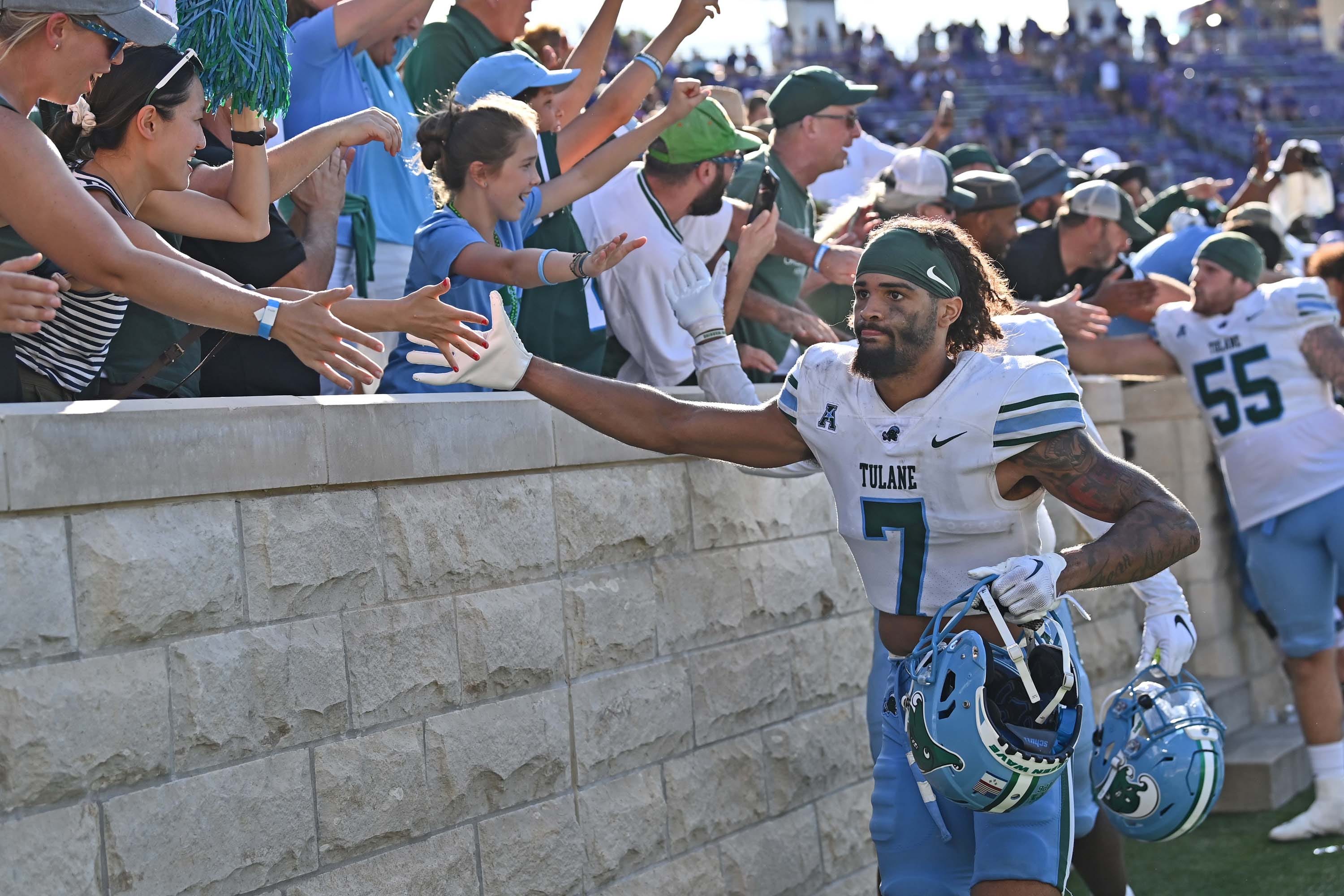 A football player walking along a crowd and high-fiving people.