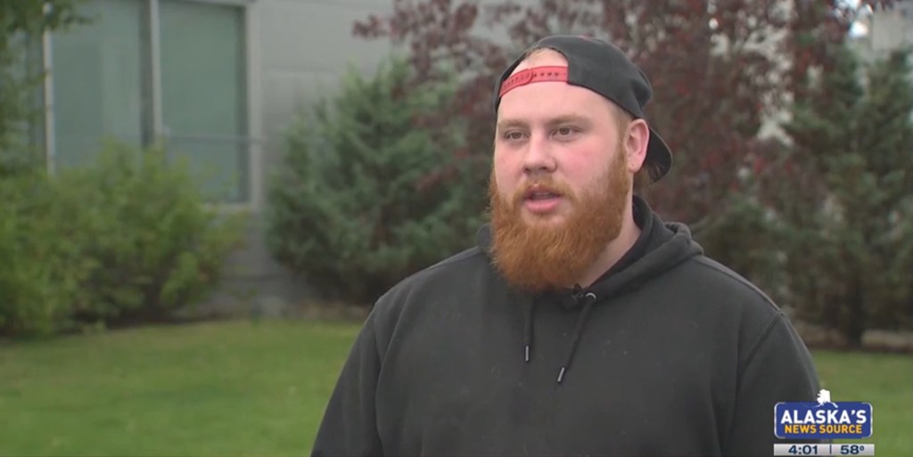 Man with red beard being interviewed outdoors.