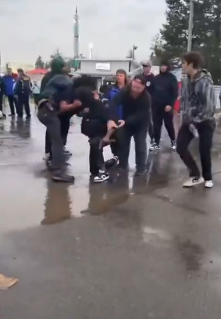 People restraining a person on the ground.