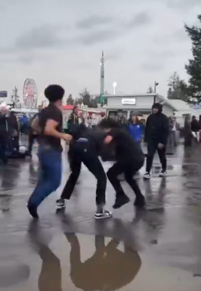 People fighting in a wet parking lot.