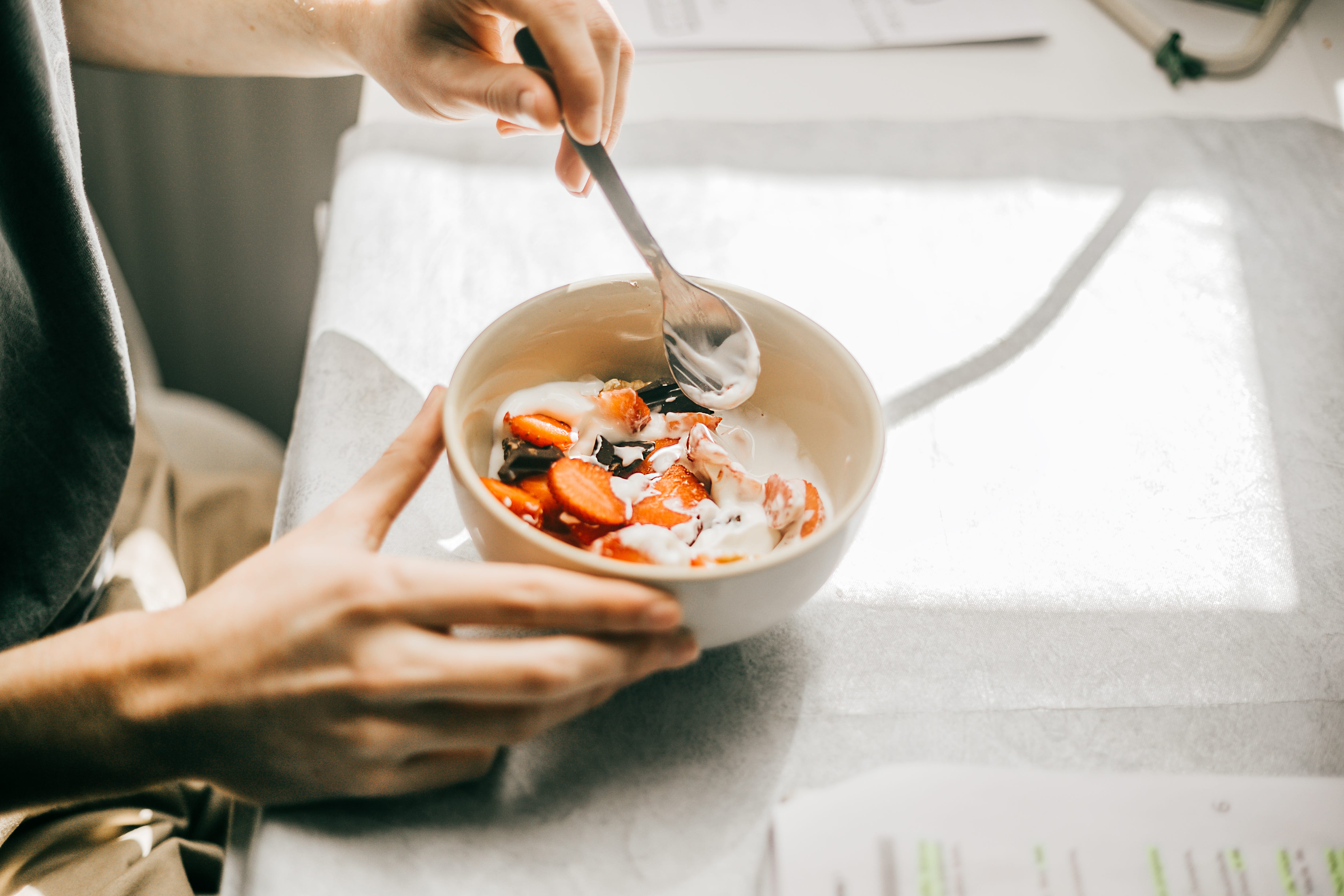 A person is eating a bowl of yogurt.