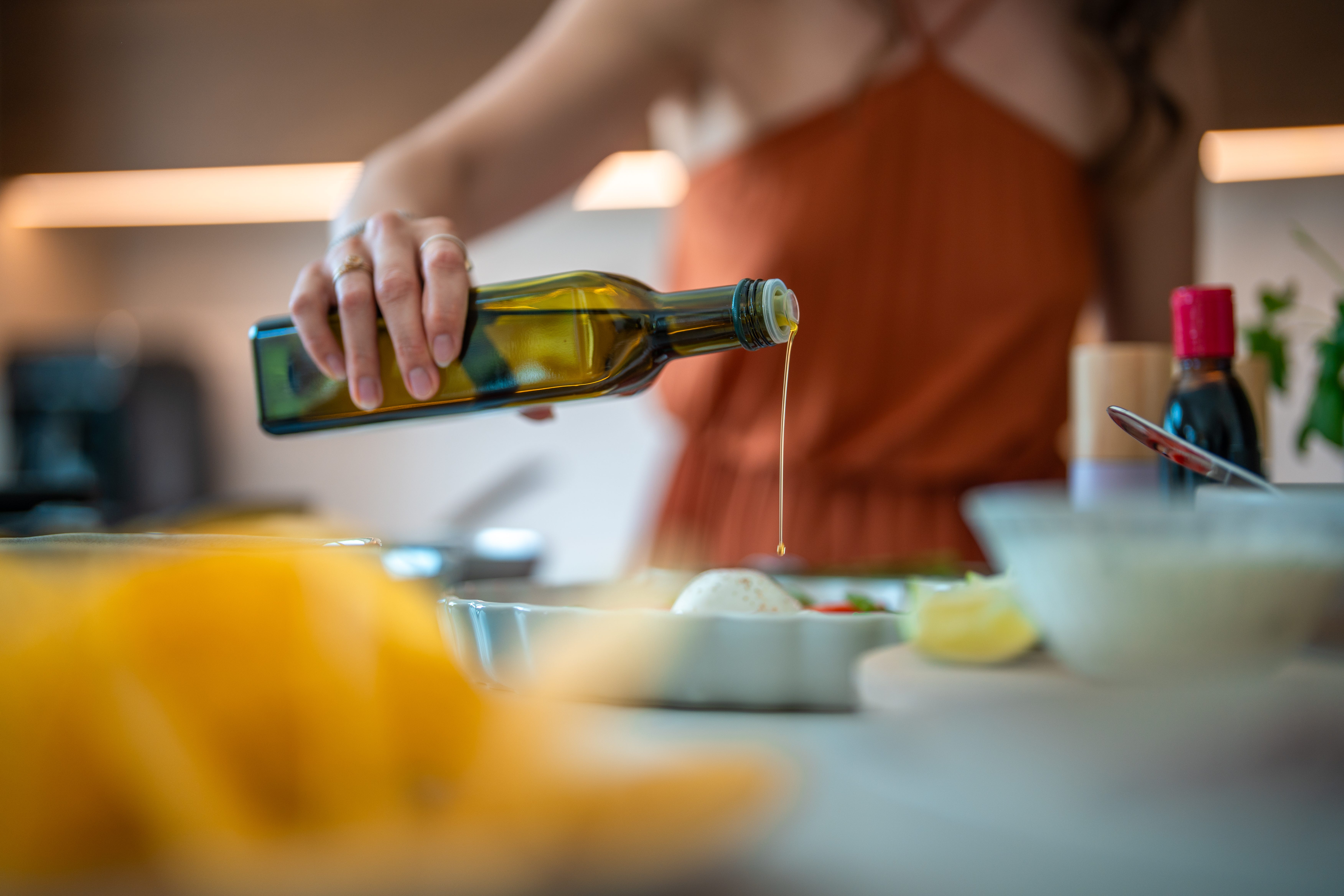 A woman pours olive oil on her meal.
