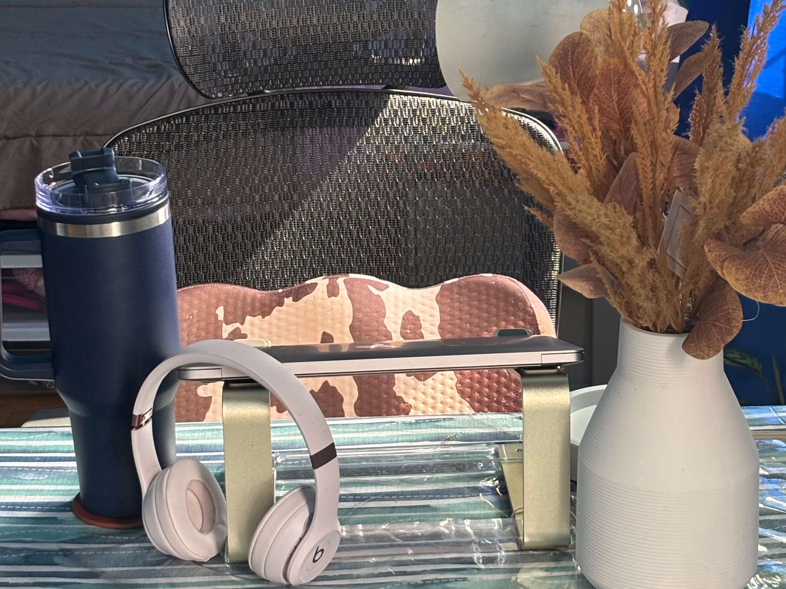 The author's work-from-home setup at her kitchen table, complete with a water bottle, Beats headphones, a laptop stand, and a plant.