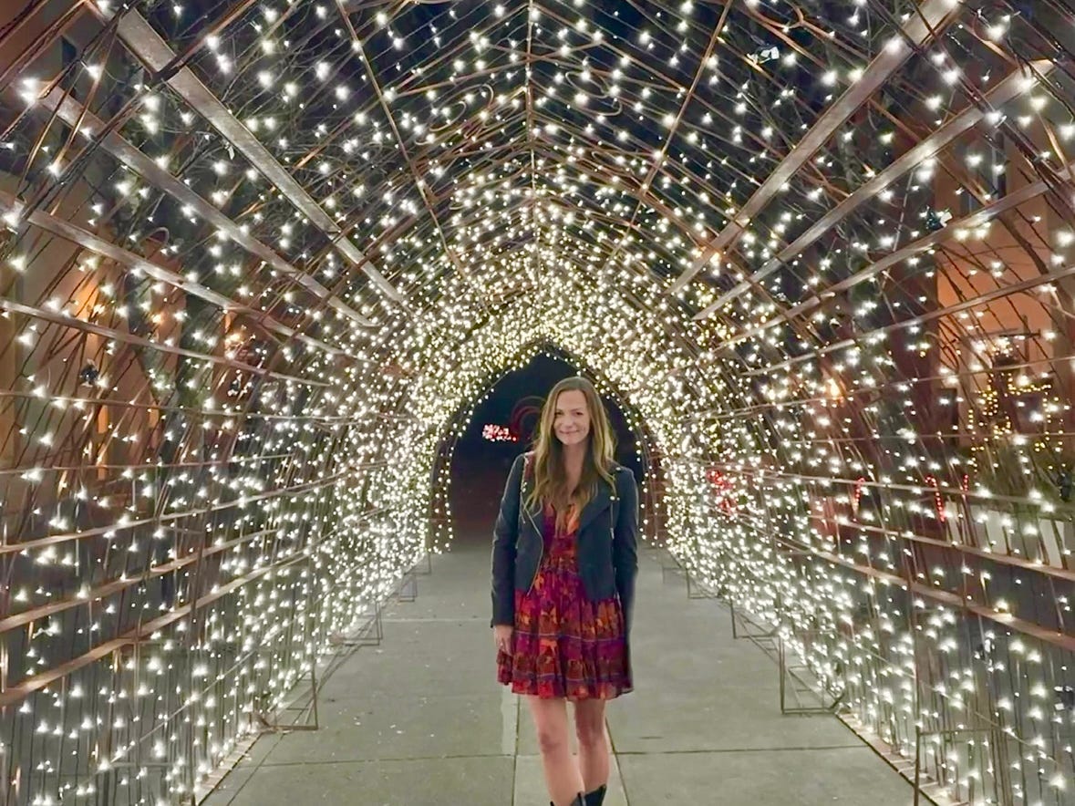 Emily standing under a tunnel of string lights in Healdsburg, California.