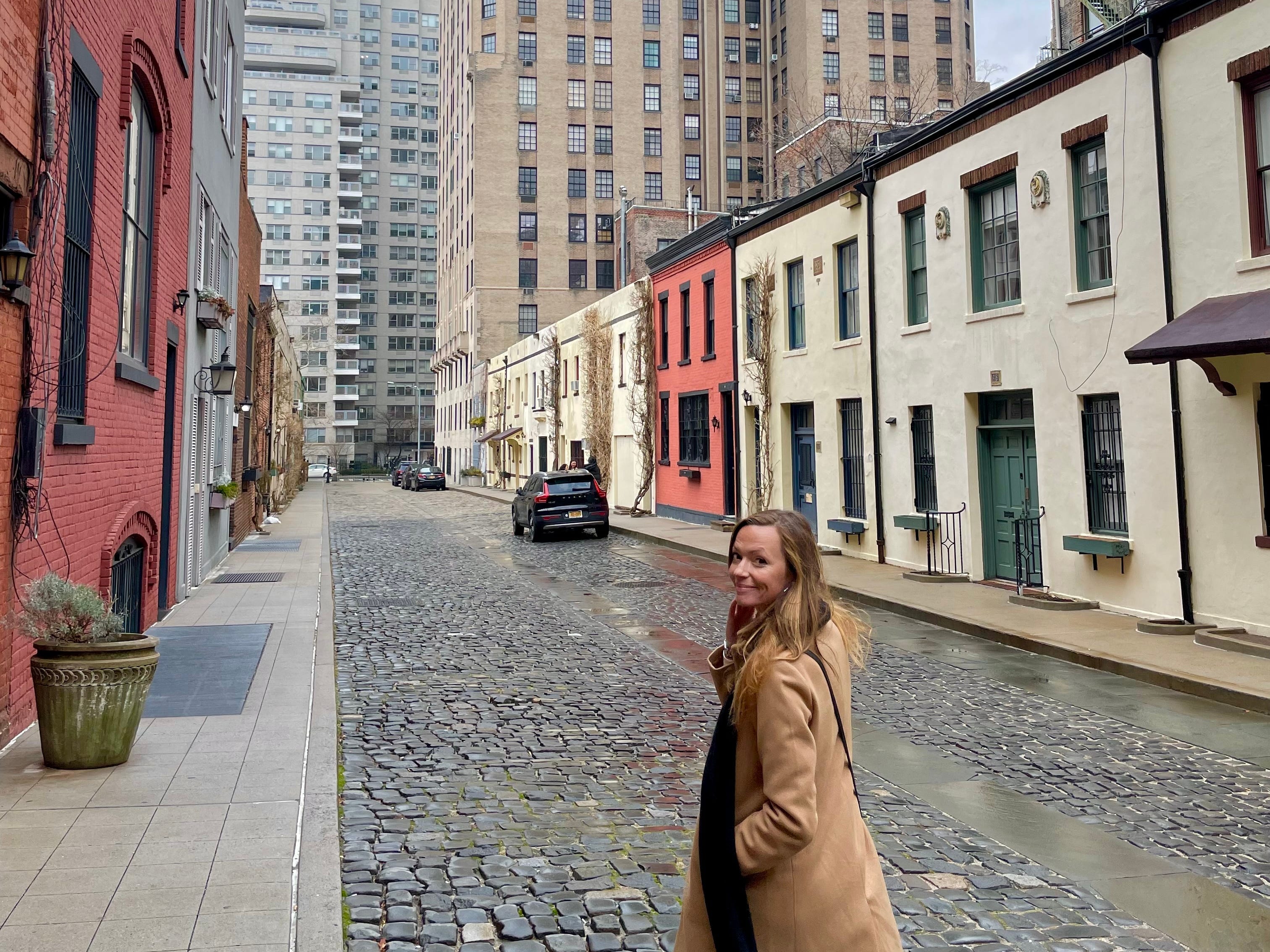 Emily walking down a stone street in New York City.