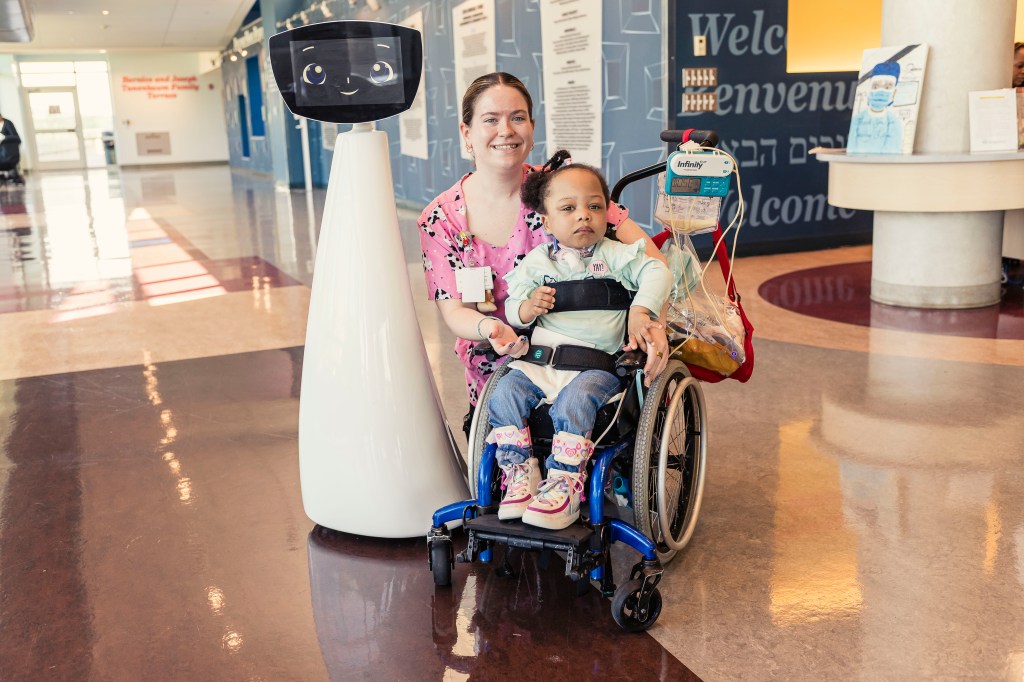 Recreation therapist with a child in a wheelchair and a robot.