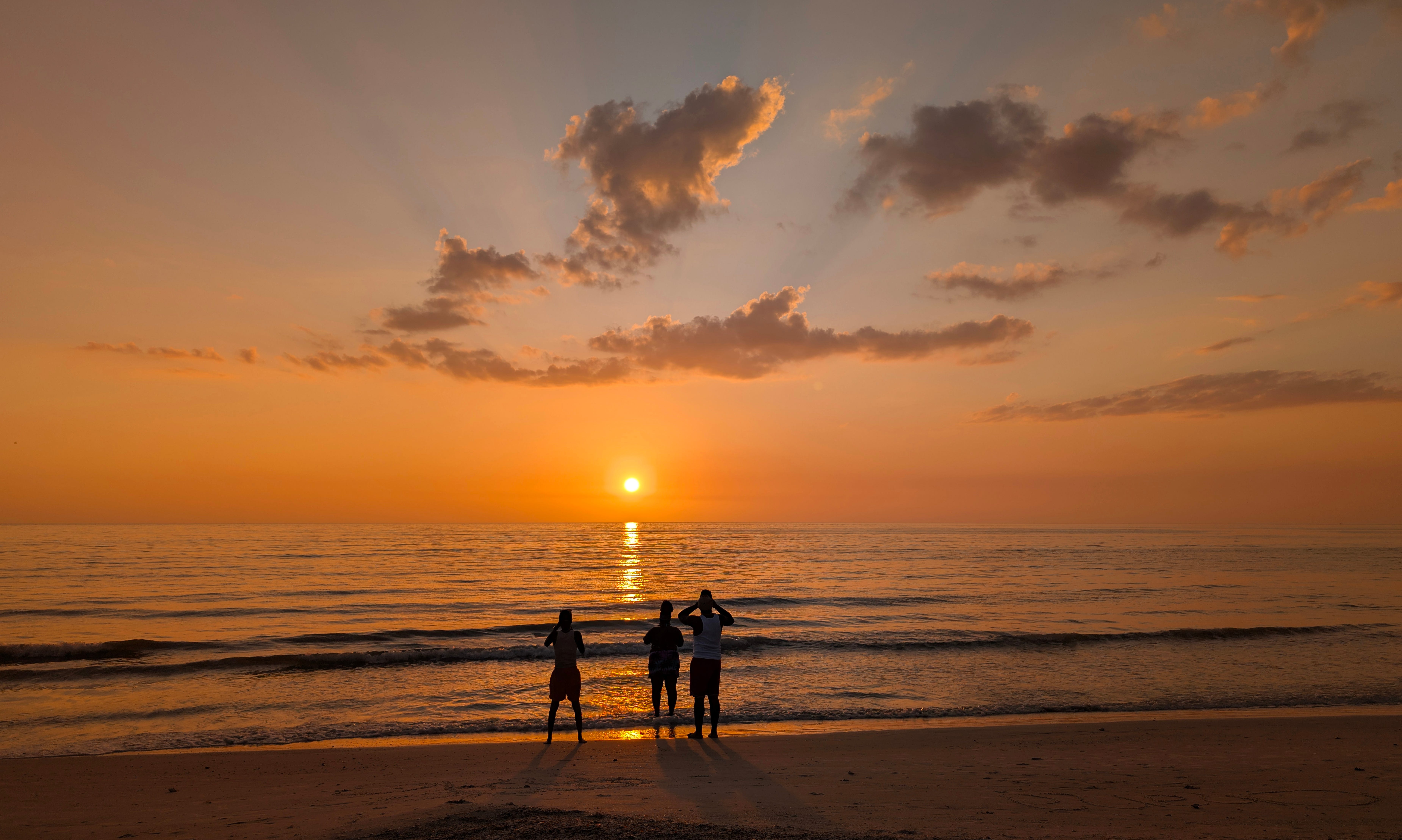People photograph the sun setting over the Gulf of America (Mexico) from Pass-A-Grille Beach on April 2, 2025, in St Petersburg, Florida.