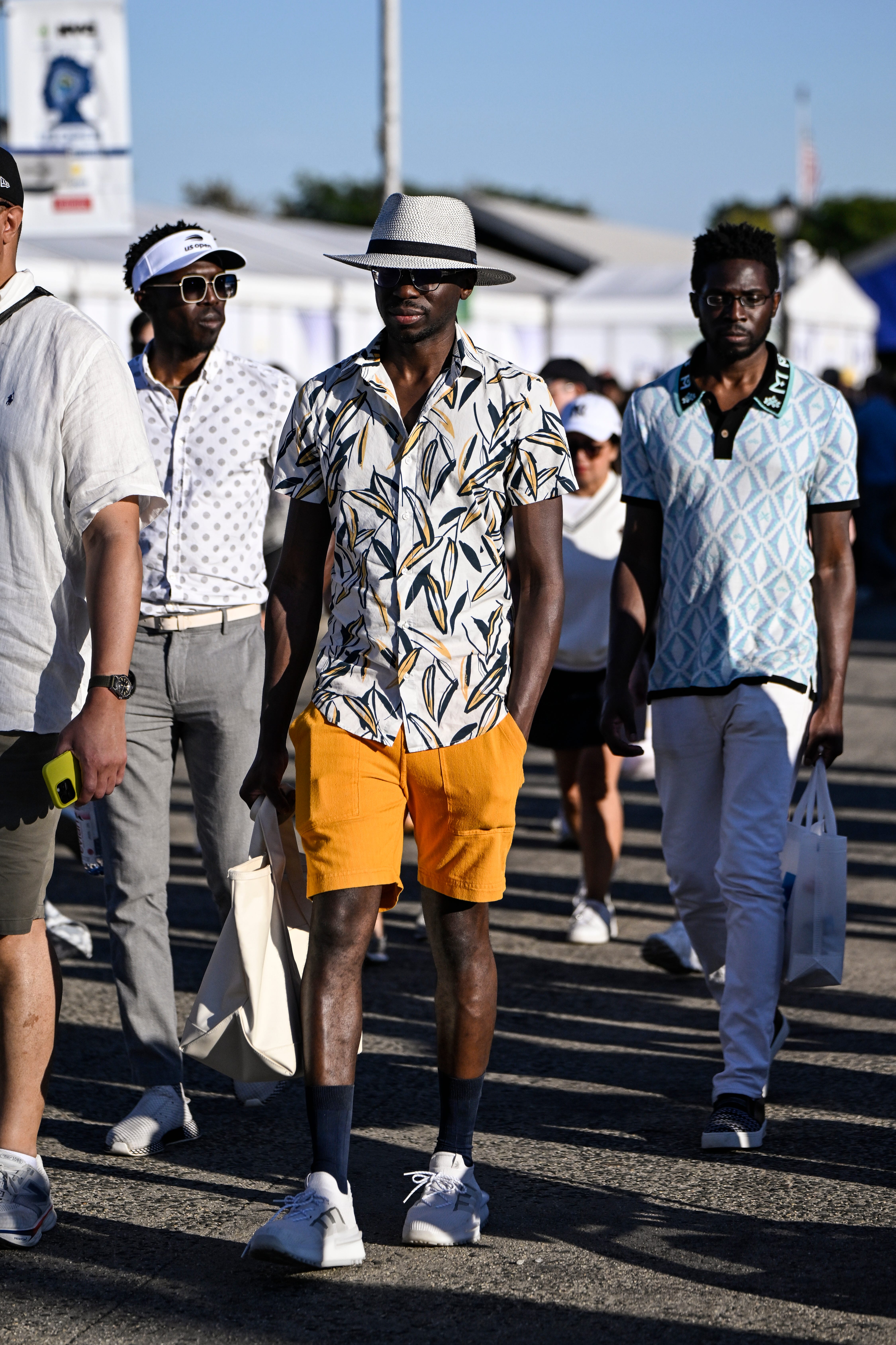 A man in a patterned shirt and orange shorts.