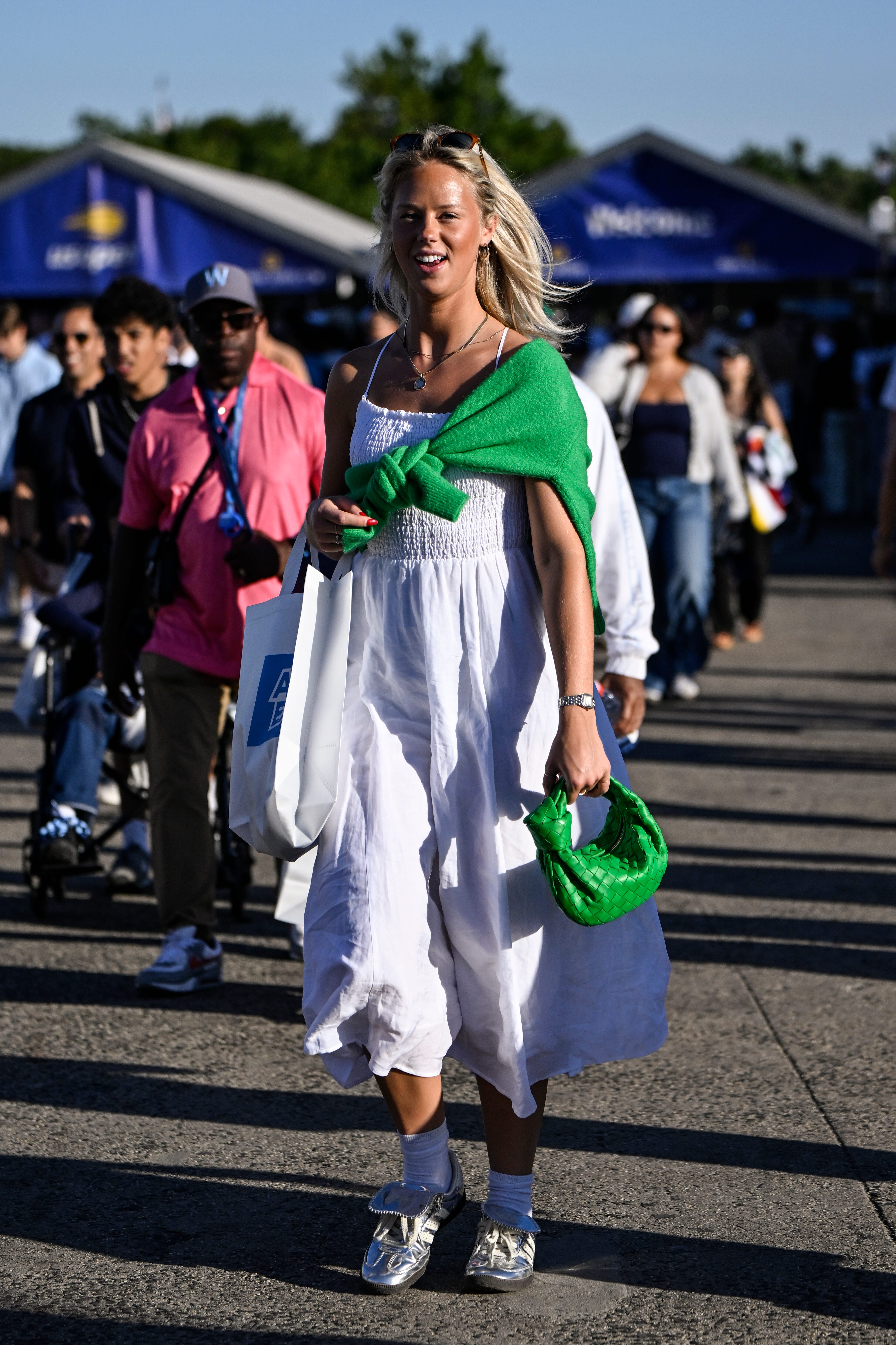 A woman in a white dress with a green sweater.