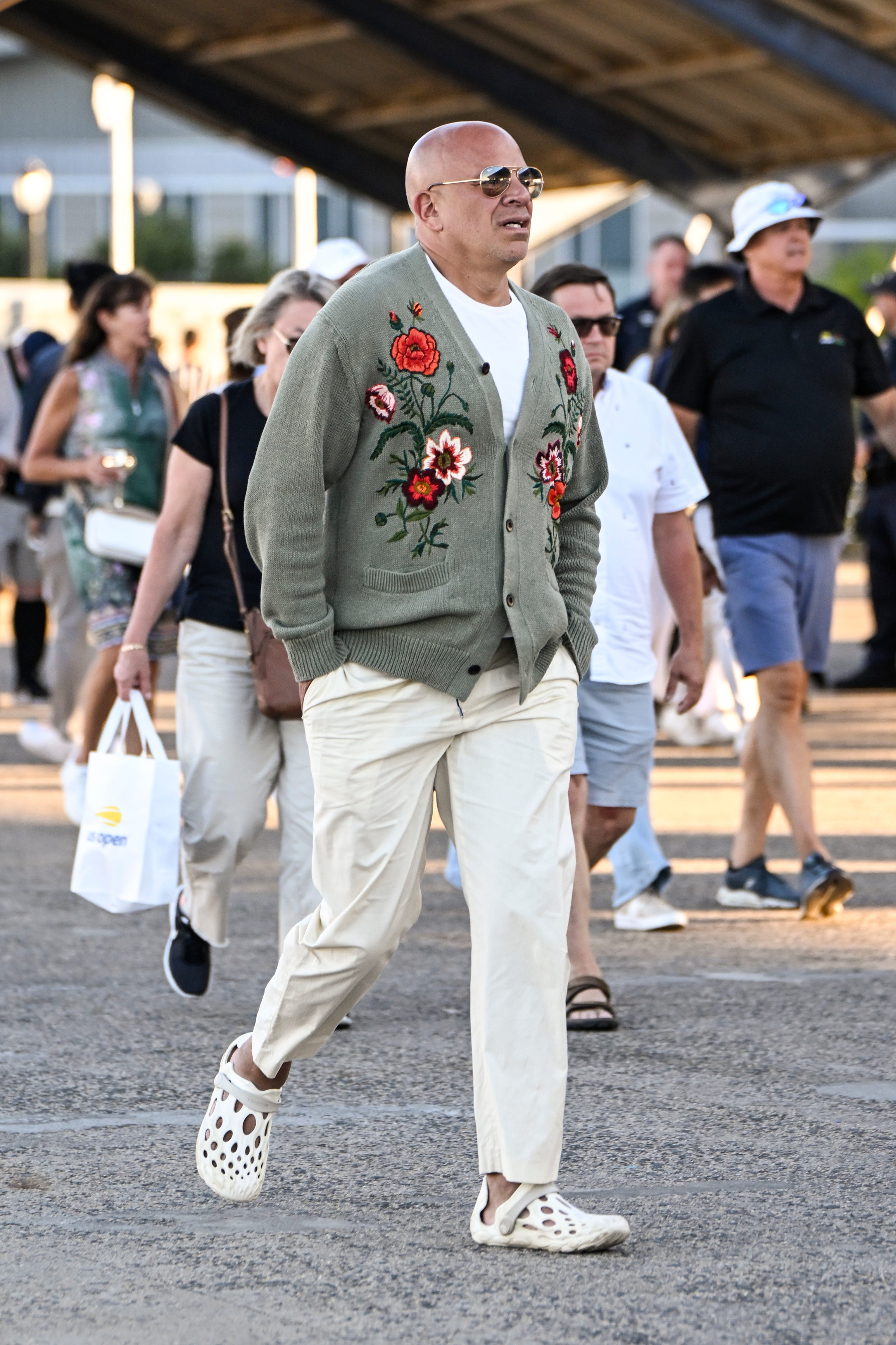 A man in cream pants and a gray floral sweater.