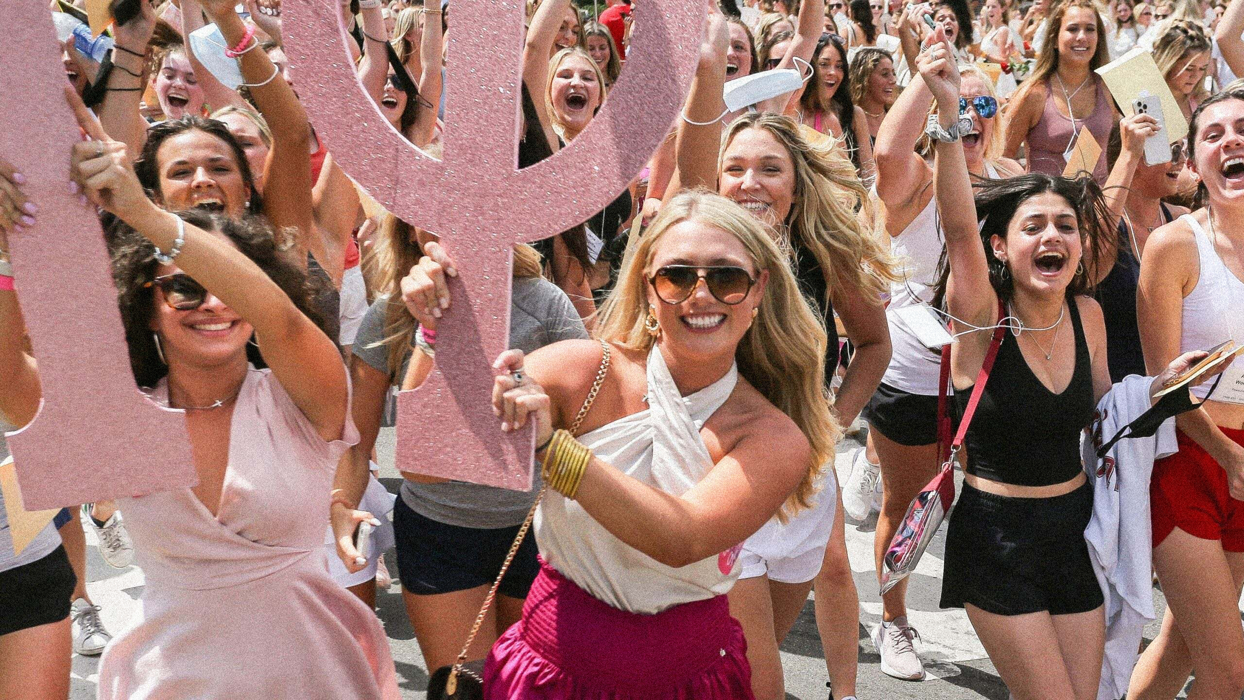 An image of sorority girls running with their Greek letters on bid day.