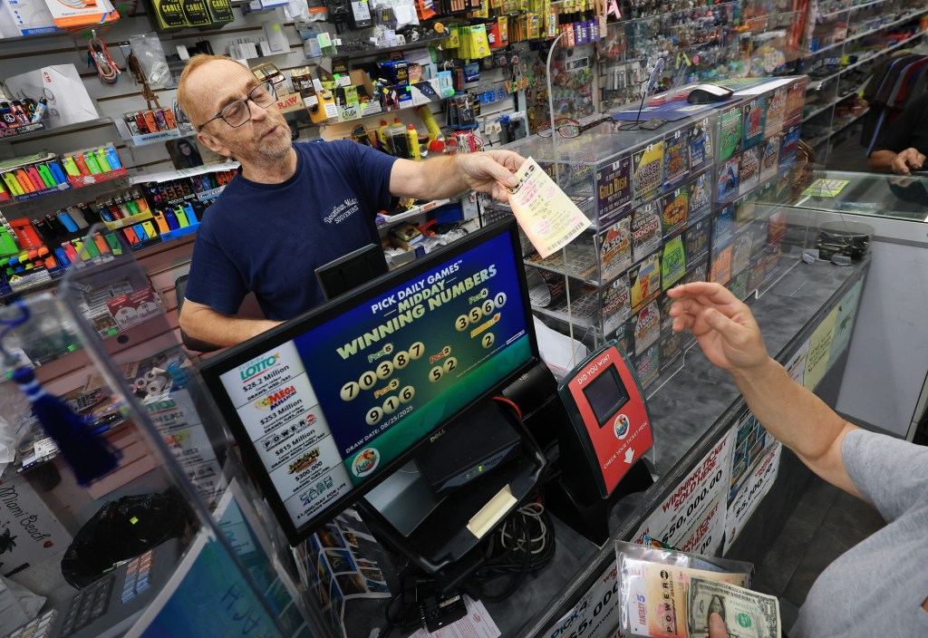 A clerk hands a customer a Powerball lottery ticket.