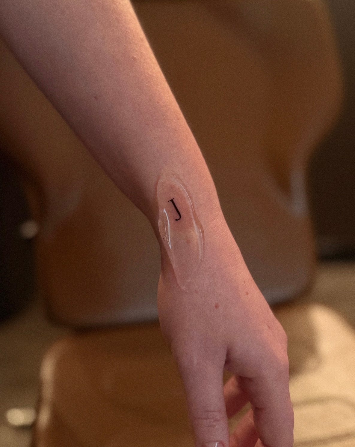 a tiny tattoo of the letter J