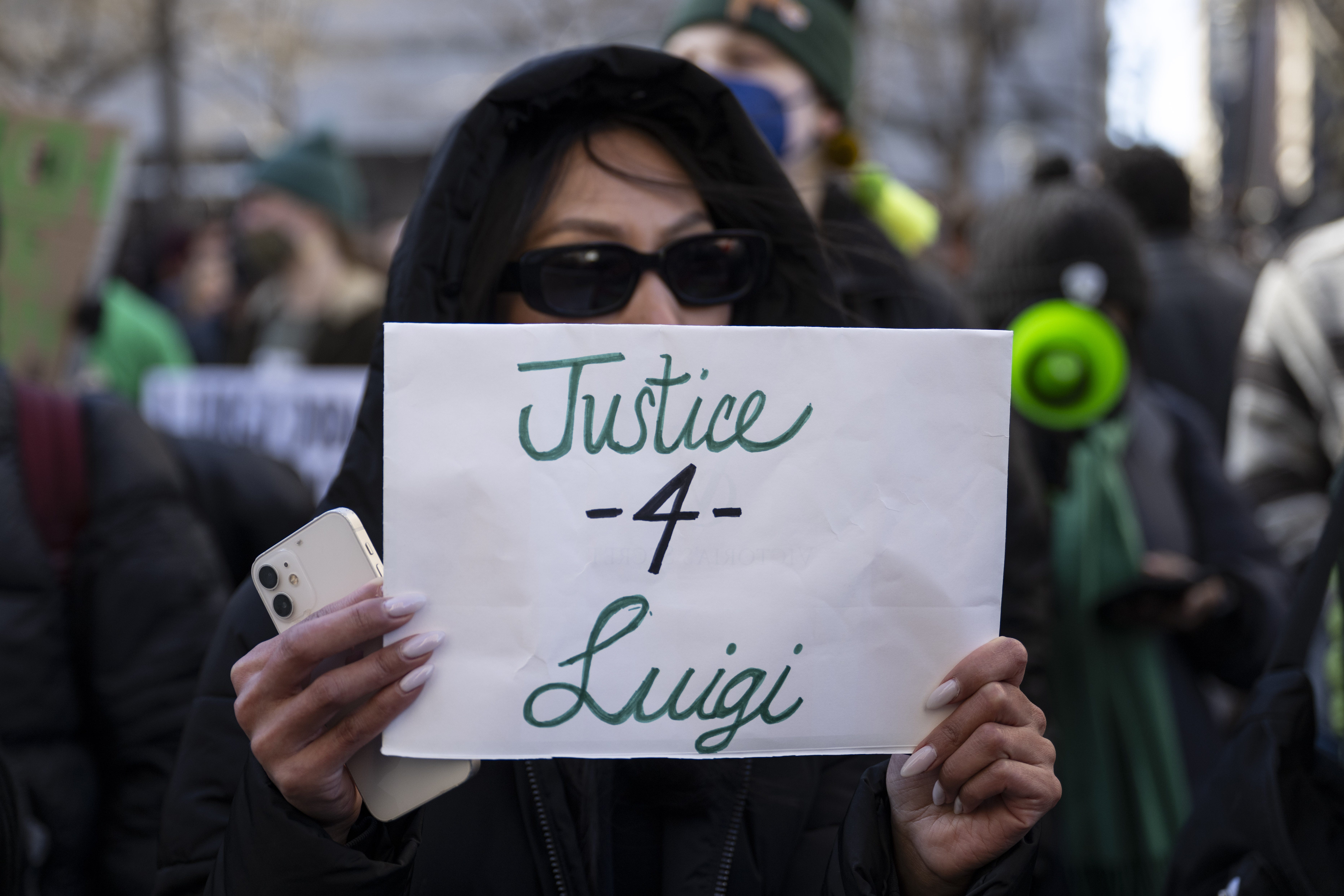 A woman holds a "Justice -4- Luigi" sign at a February 2025 gathering of dozens of supporters outside state court in Manhattan.