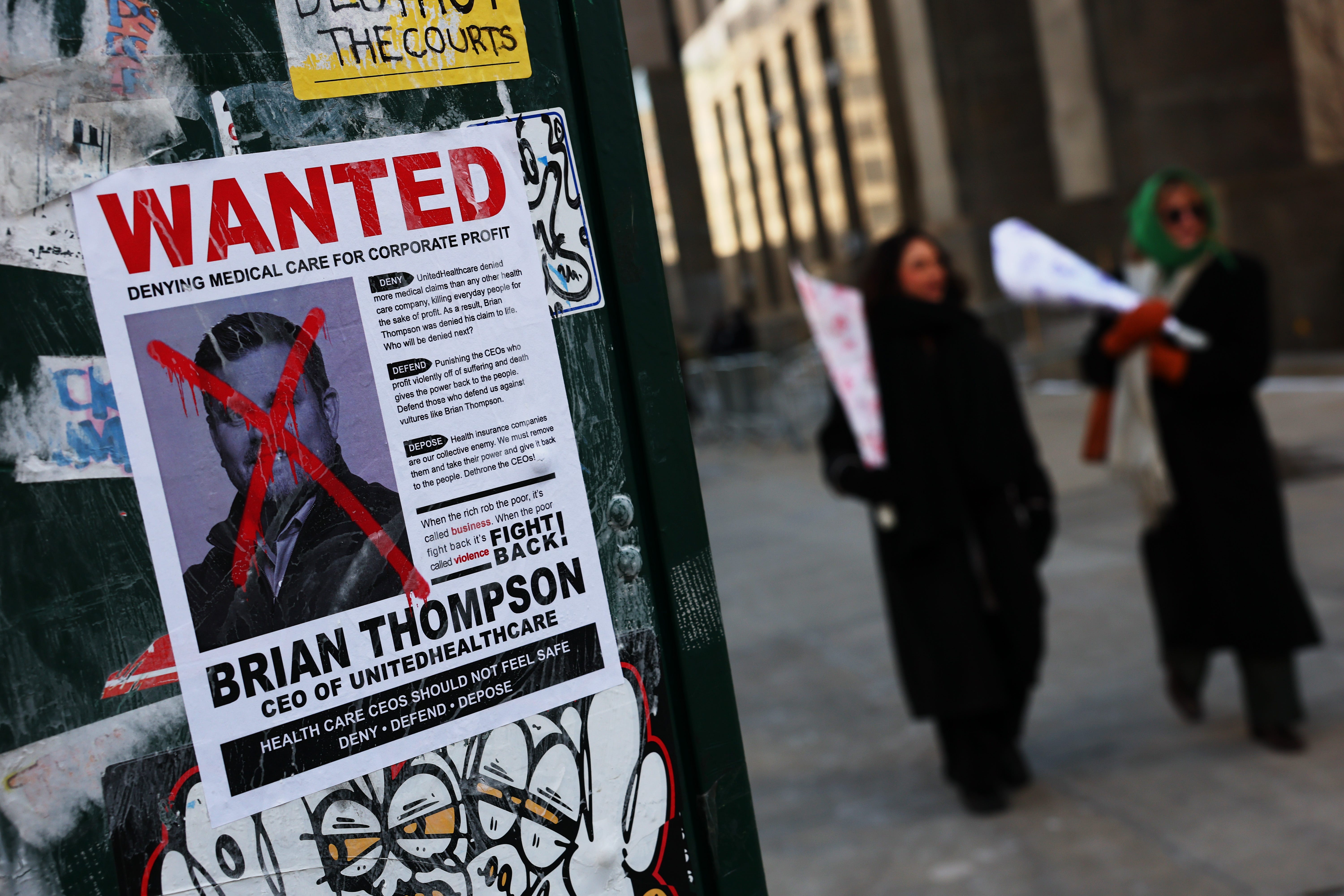 A "Wanted" poster shows murdered UnitedHealthcare CEO Brian Thompson with an "X" across his face. The sign was posted near state court in Manhattan in February.