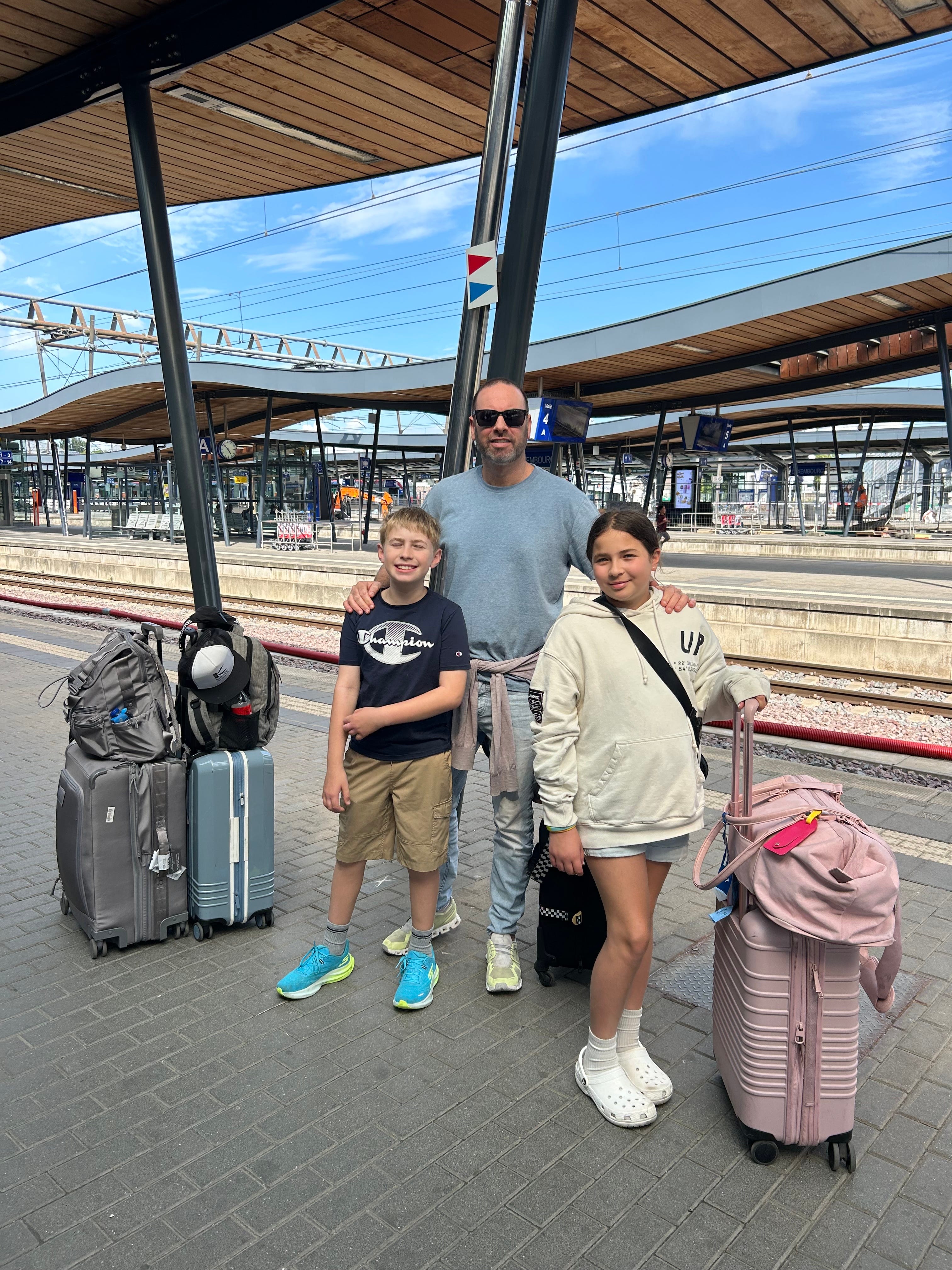 The author's kids and husband with luggage at a train station in Europe.