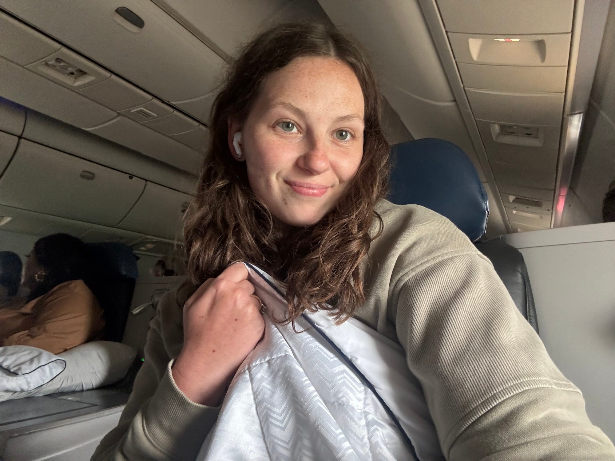 A selfie of a woman with a blanket on a plane.
