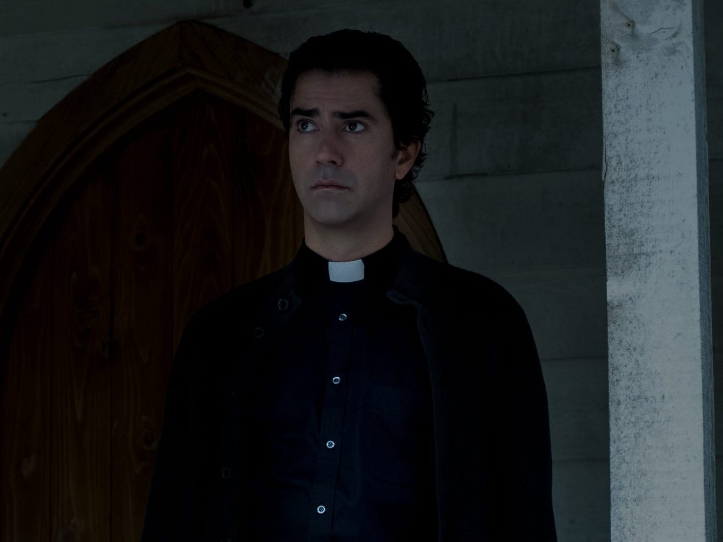 father paul standing on a front porch on midnight mass on netflix