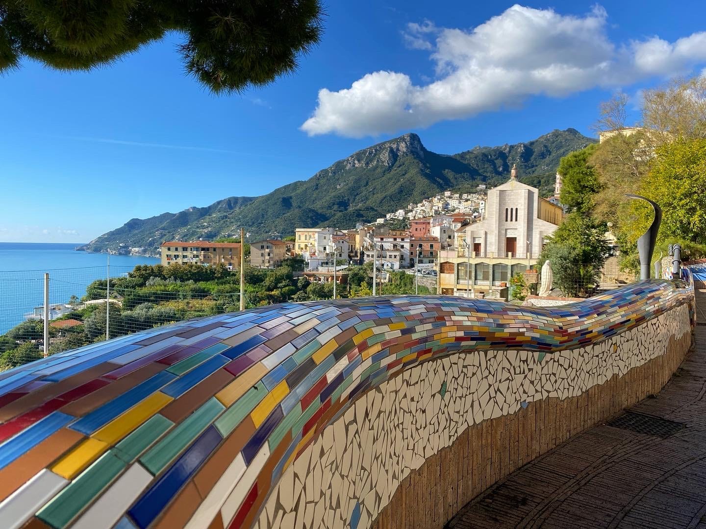 colorful tiles along ledge next to water with mountains in distance