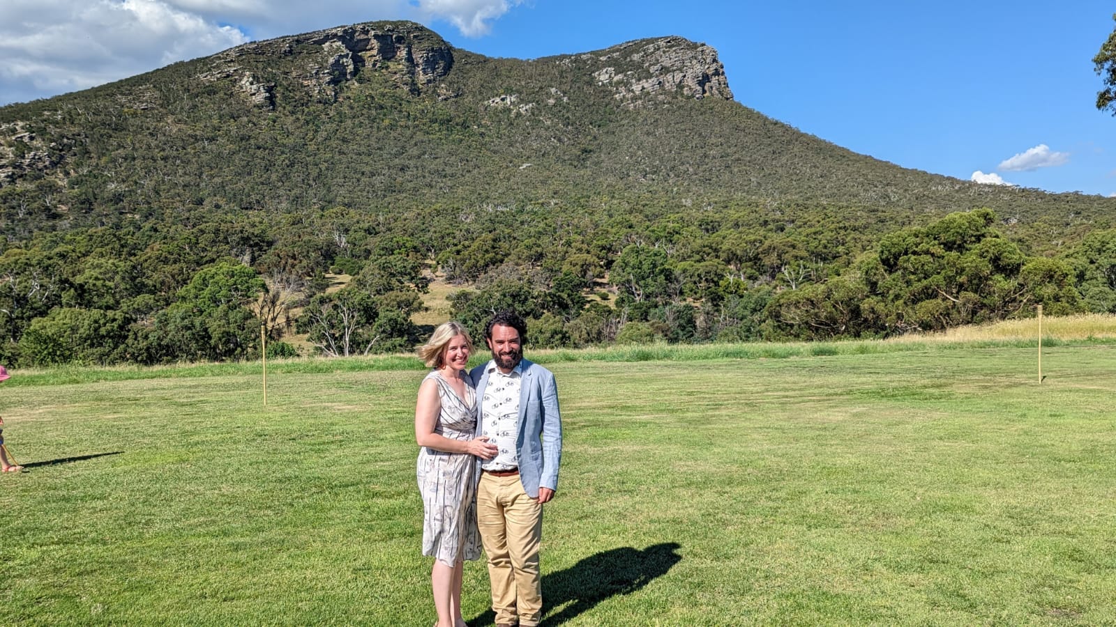 Author Tegan Forder posing with man in blazer in front of green hills