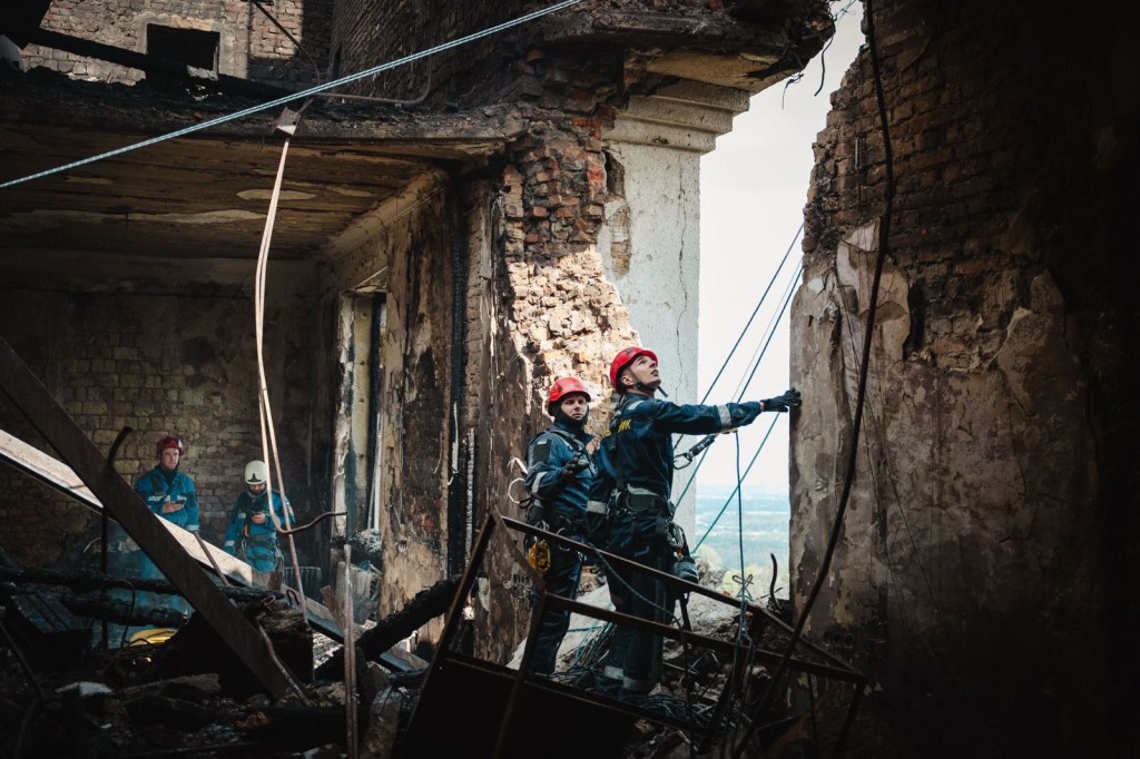 Rescue workers assess damage inside a bombed-out building.