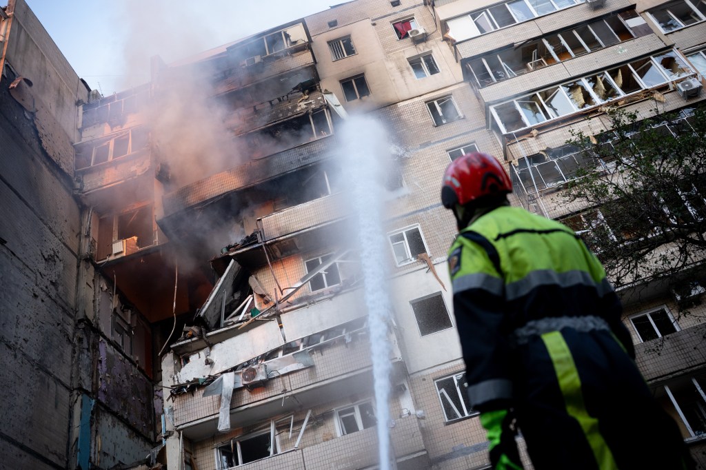 Firefighter extinguishing a fire in a damaged residential building in Kyiv, Ukraine.