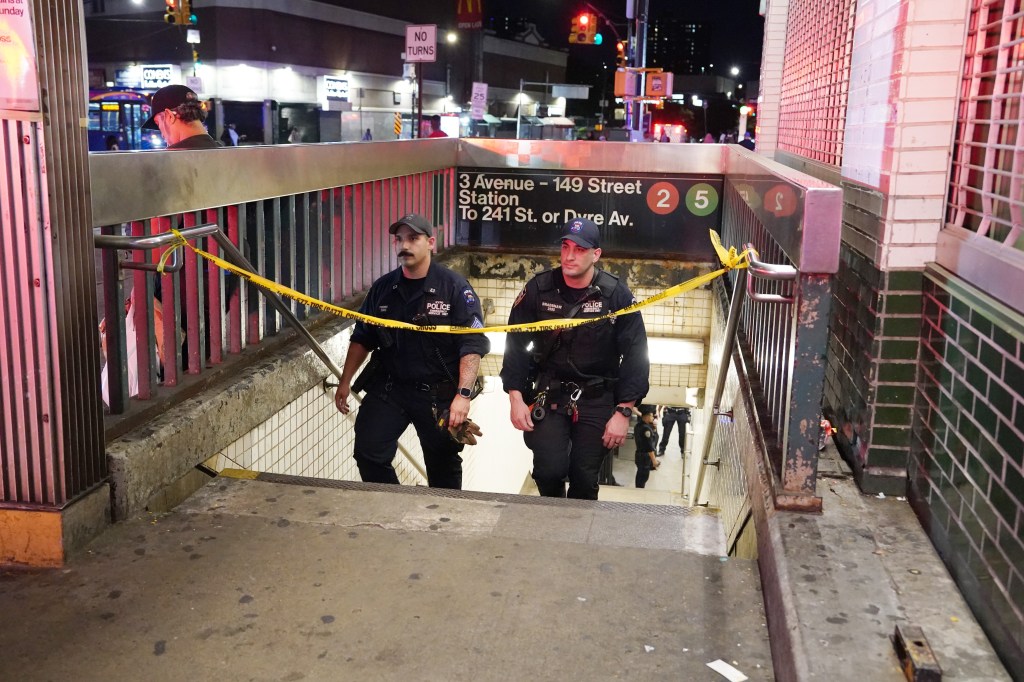 Police officers at a subway station entrance following a fatality.