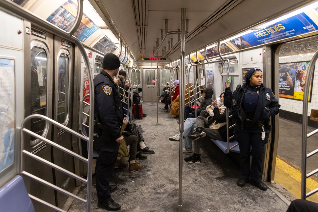 Two NYPD officers on patrol in a New York City subway car.