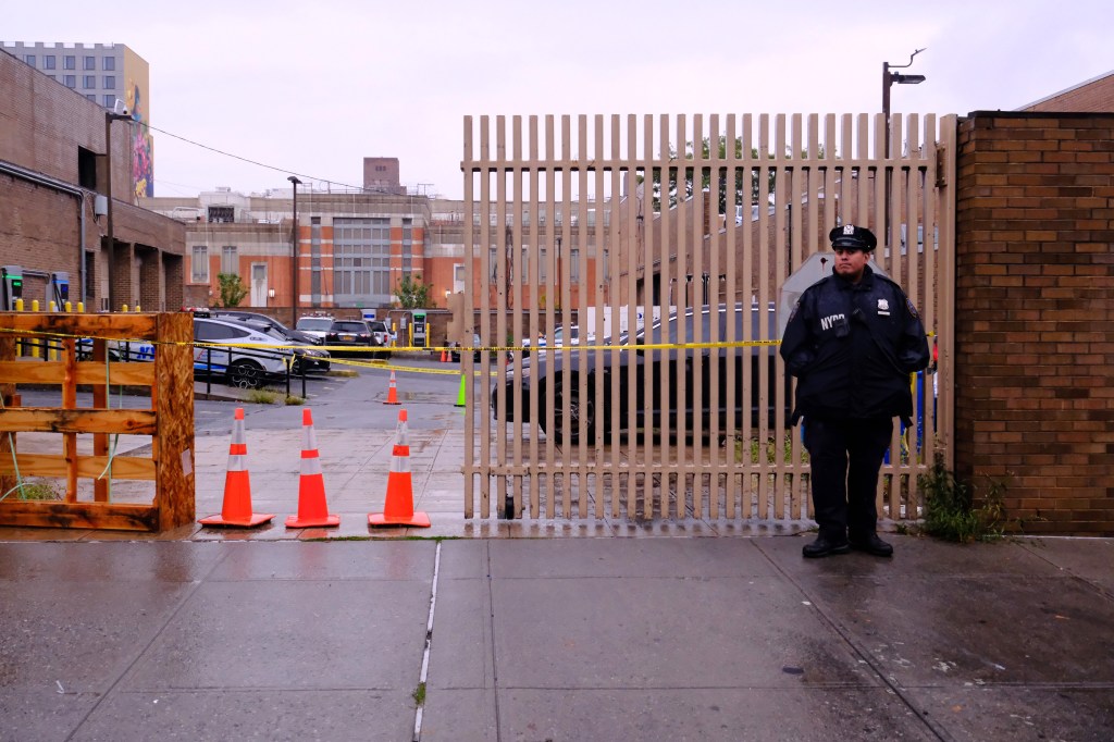 NYPD officer standing guard outside a precinct following a shooting.