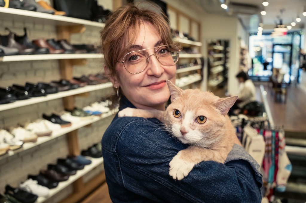 Woman holding a cat in a shoe store.