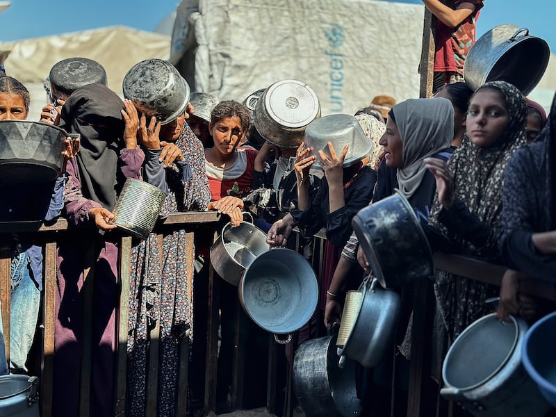 Displaced Palestinians wait in long lines for a meal.