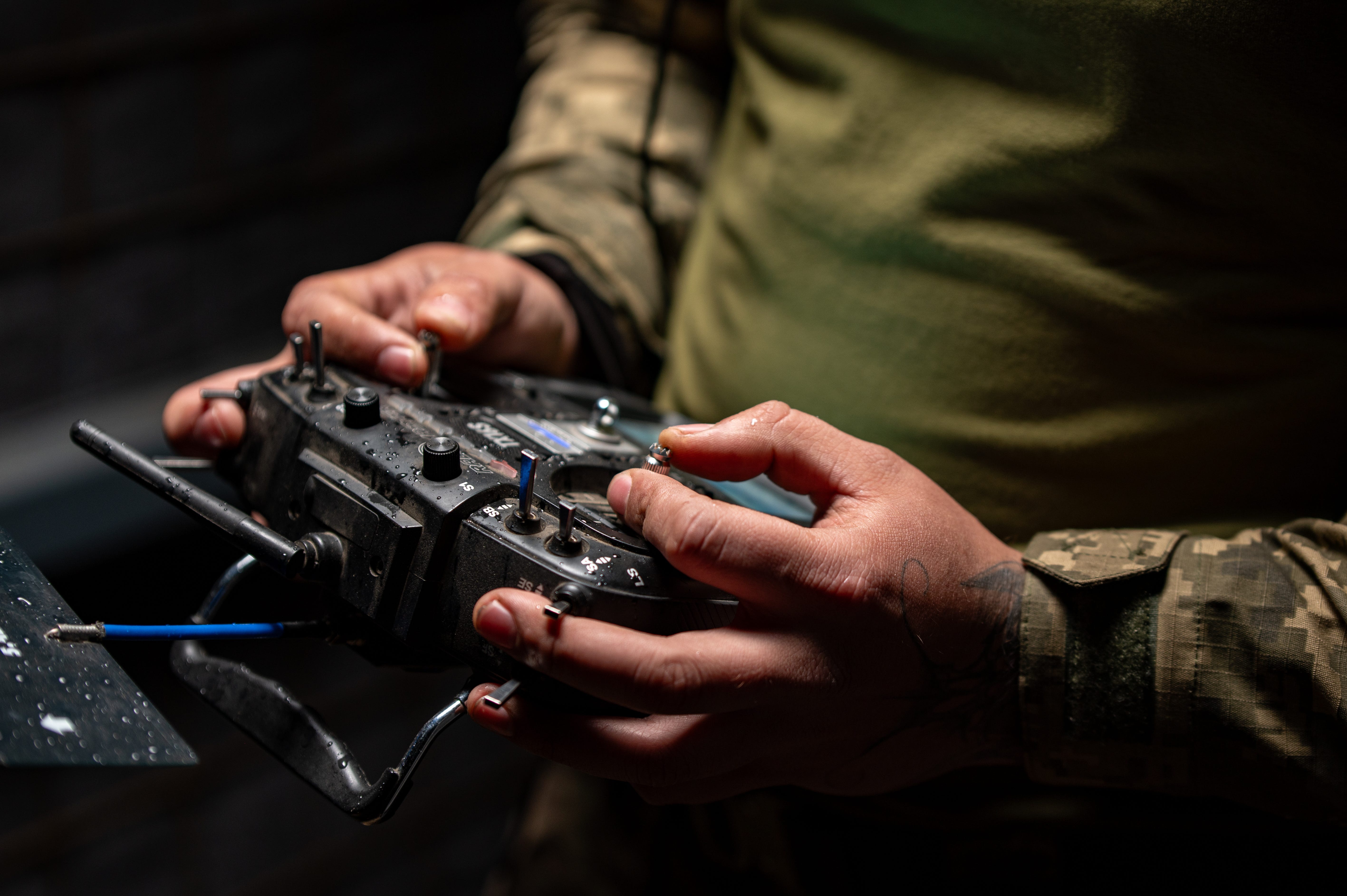 A Ukrainian drone operator holds a controller with his thumbs and forefinger on both control sticks and his middle fingers on the edges of the controller.
