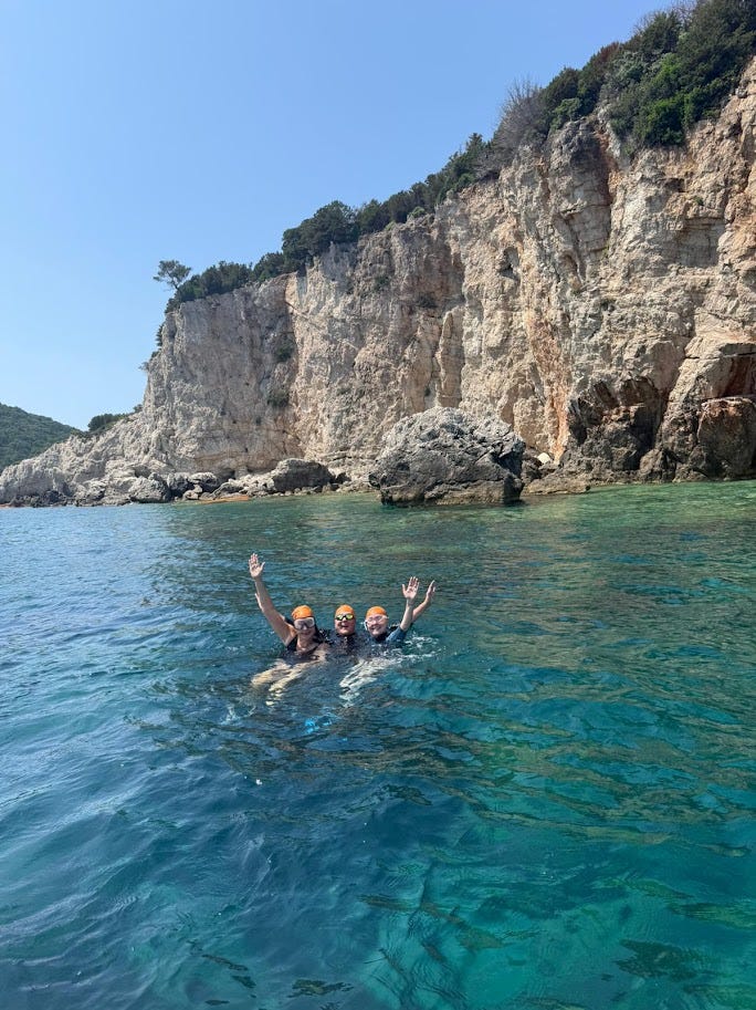 Three woman wearing orange swim caps in the sea in Greece.