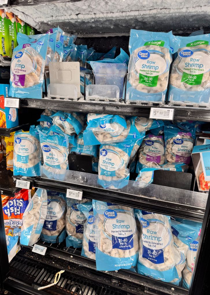 Frozen Great Value shrimp packages on a shelf in a freezer.