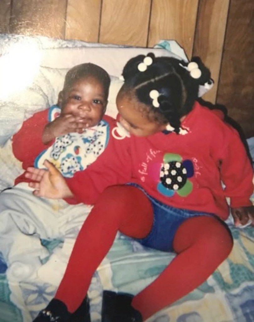 Photo of a young girl and baby sitting together.