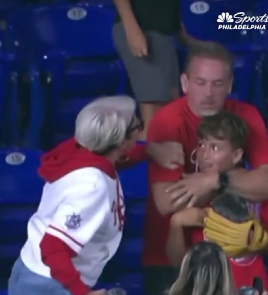 A Phillies fan aggressively tries to take a home run ball from a young boy.