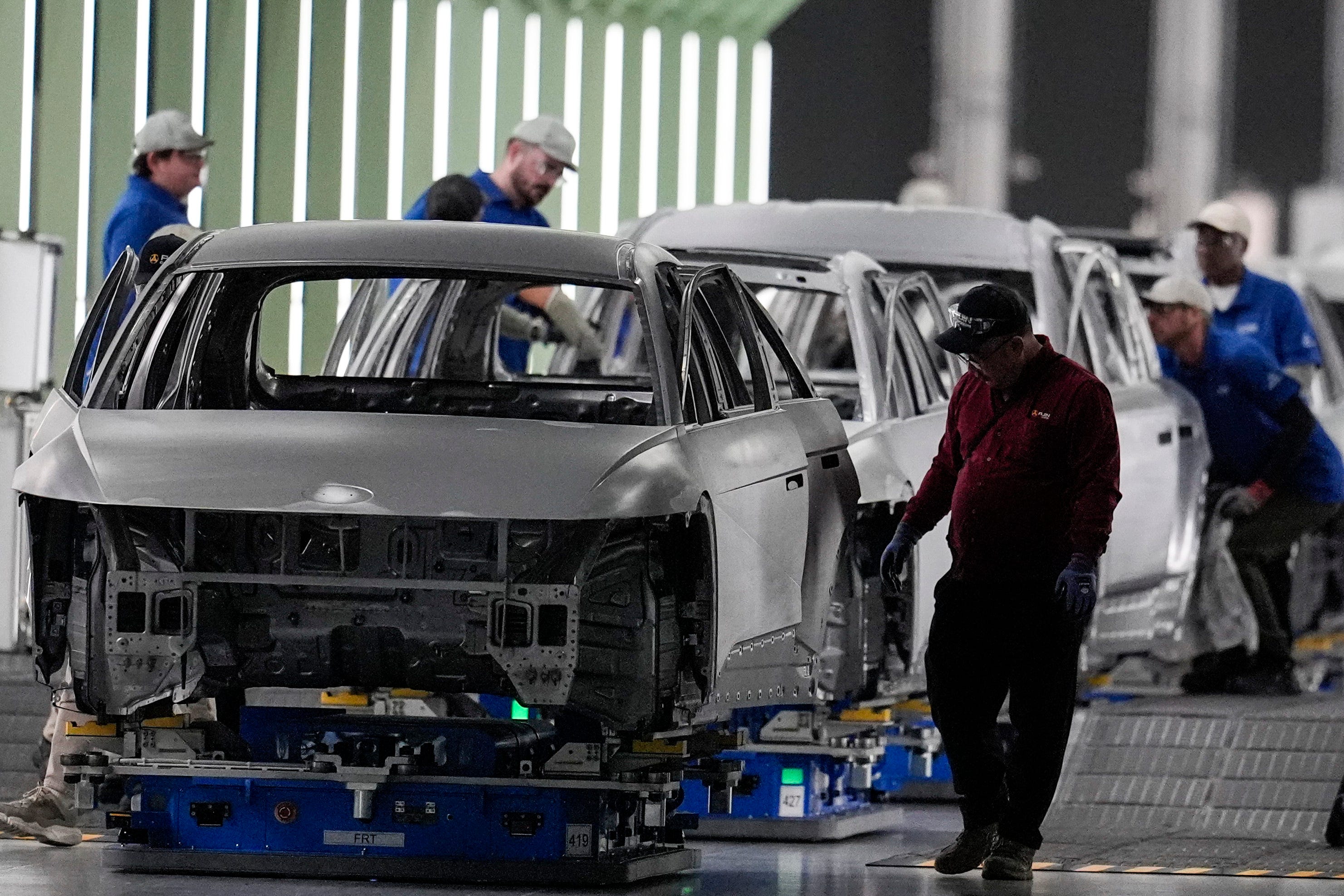 Employees work the line of a car manufactory.