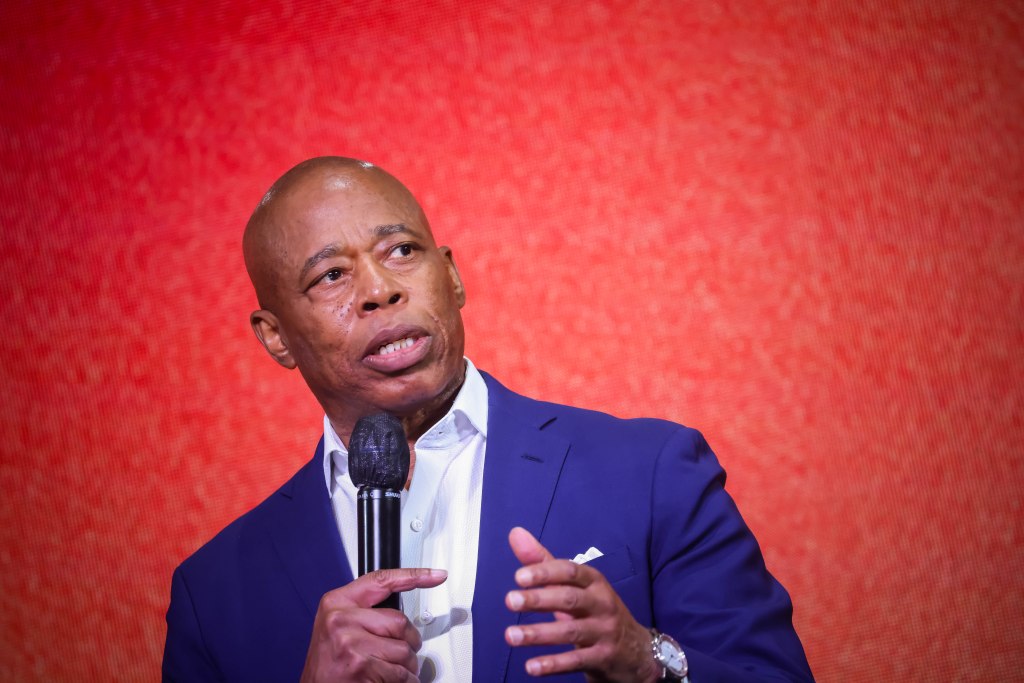NYC Mayor Eric Adams speaking at a microphone.