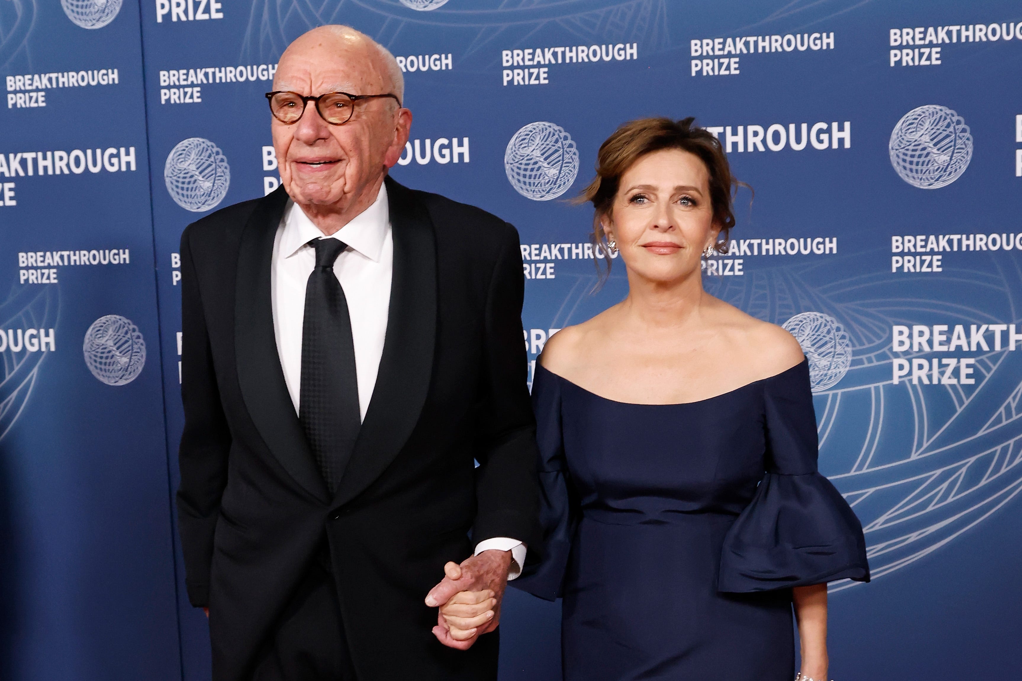 Rupert Murdoch and his wife holding hands and dressed up at an event.