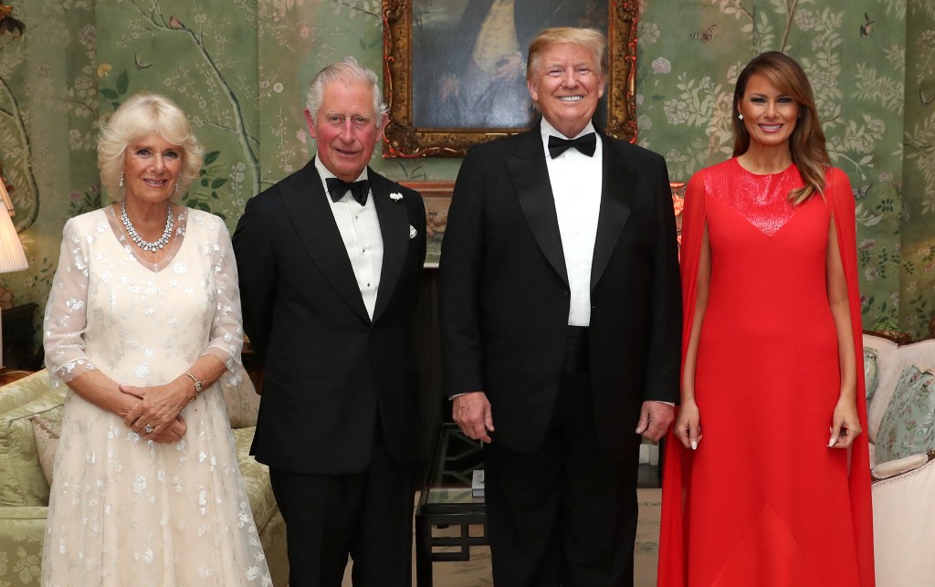 Donald Trump in a blue suit and blue tie, Melania Trump in a white suit with black trim and a white hat with black trim, Prince Andrew in a black suit and blue tie.