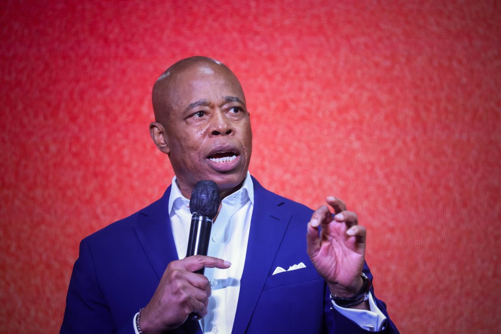 NYC Mayor Eric Adams speaking at a microphone.